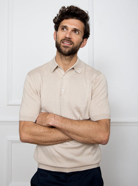 Man wearing almond beige short sleeved polo sweater knit in 100% luxury and premium merino wool.